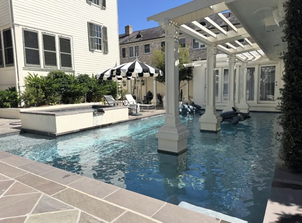 Courtyard swimming pool with pergola columns and spillover spa at a New Orleans home