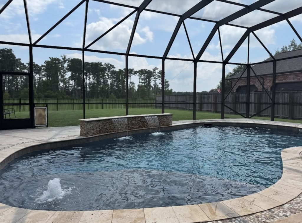 Screened-in backyard pool with stacked-stone waterfall feature